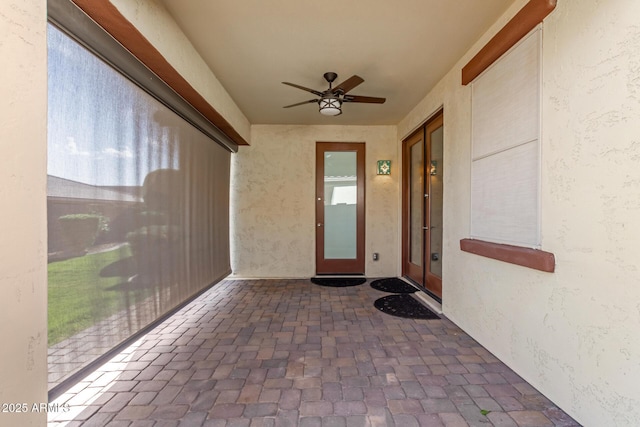 view of exterior entry featuring a patio area, stucco siding, and ceiling fan