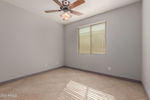spare room featuring baseboards, ceiling fan, and light tile patterned floors
