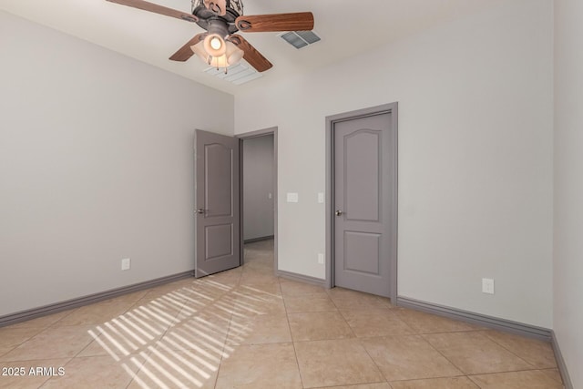 empty room featuring light tile patterned flooring, baseboards, ceiling fan, and visible vents