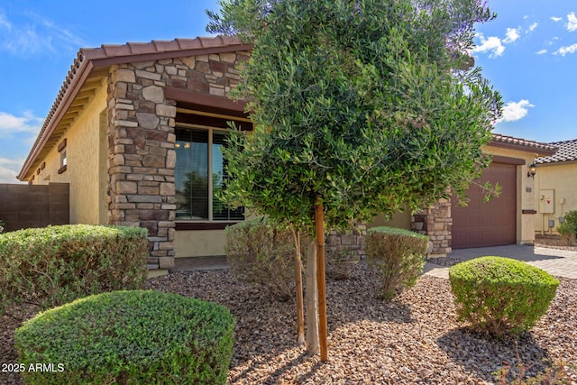 view of front of home with driveway, stone siding, stucco siding, a tiled roof, and a garage