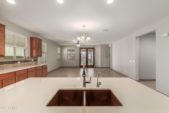 kitchen featuring light countertops, a sink, a chandelier, and brown cabinets