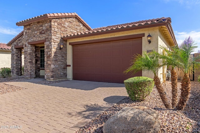view of front of house with driveway, stucco siding, a tiled roof, and a garage