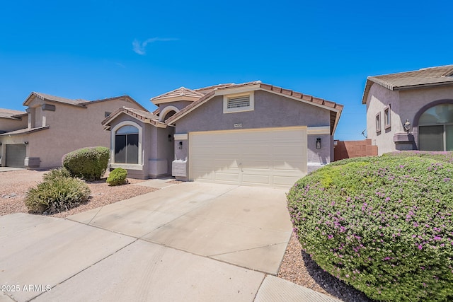 view of front facade with stucco siding, an attached garage, driveway, and a tiled roof