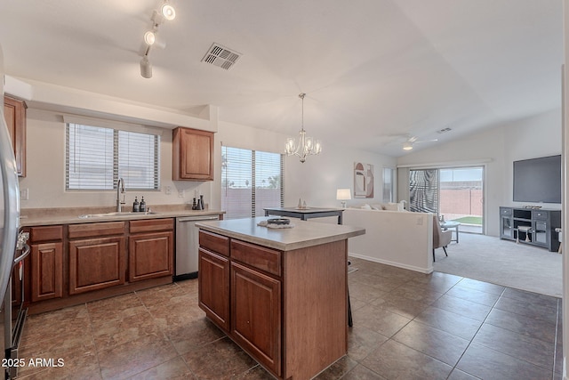 kitchen with appliances with stainless steel finishes, a sink, open floor plan, a kitchen island, and light countertops