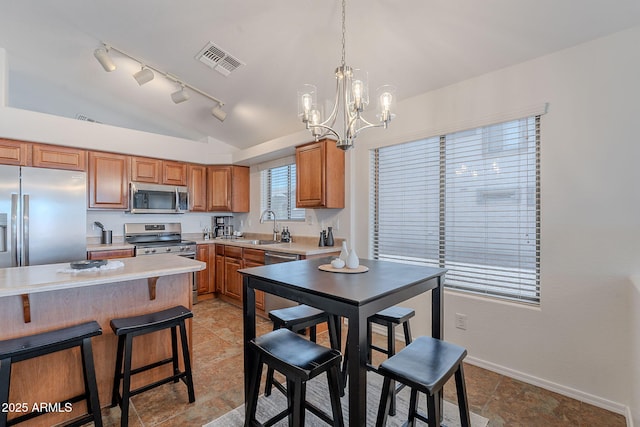 kitchen featuring appliances with stainless steel finishes, a sink, vaulted ceiling, a chandelier, and light countertops