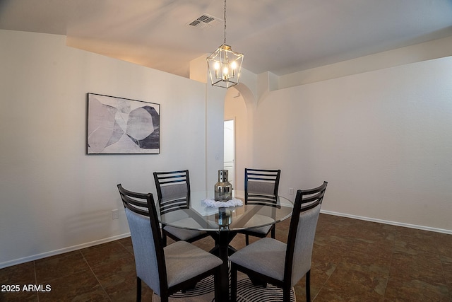 dining room with arched walkways, baseboards, a chandelier, and stone finish flooring