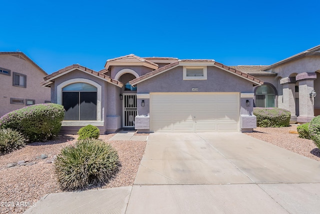view of front facade featuring an attached garage, concrete driveway, stucco siding, and a tile roof