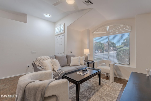 living area with plenty of natural light, lofted ceiling, a ceiling fan, and baseboards