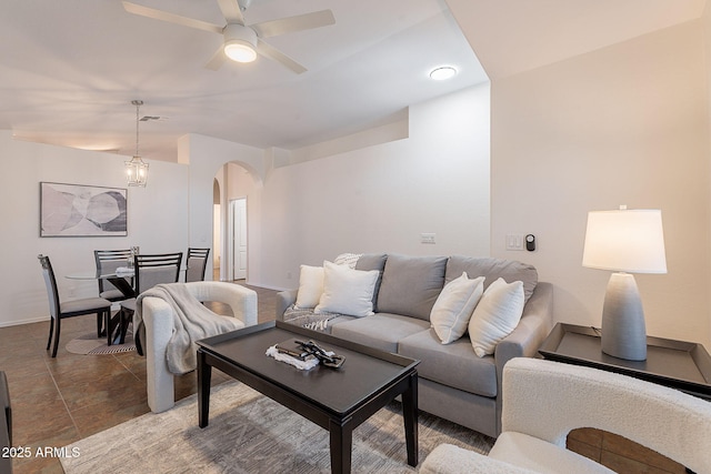 living room with arched walkways, a ceiling fan, and baseboards