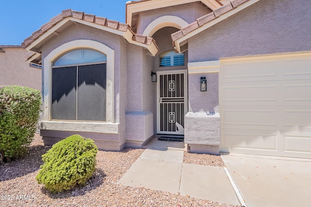 view of exterior entry with stucco siding and an attached garage