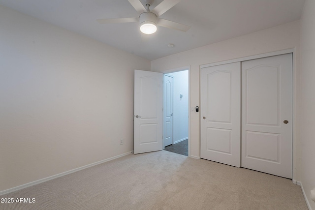 unfurnished bedroom featuring light colored carpet, baseboards, a closet, and a ceiling fan