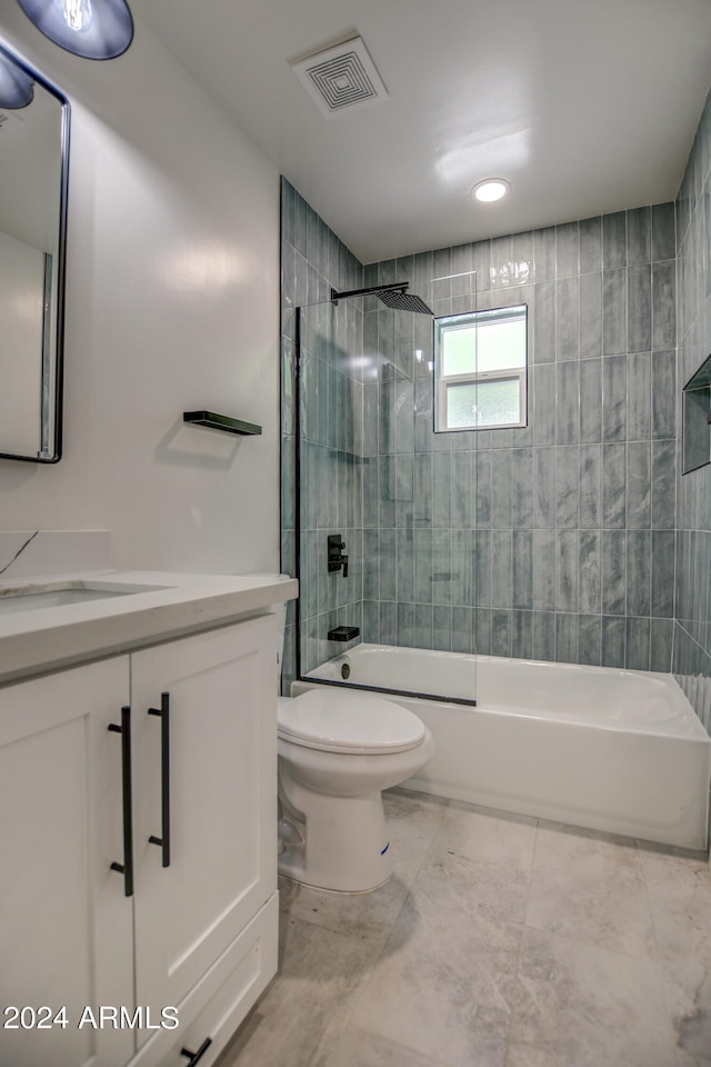 full bathroom with tiled shower / bath combo, tile floors, vanity, and toilet