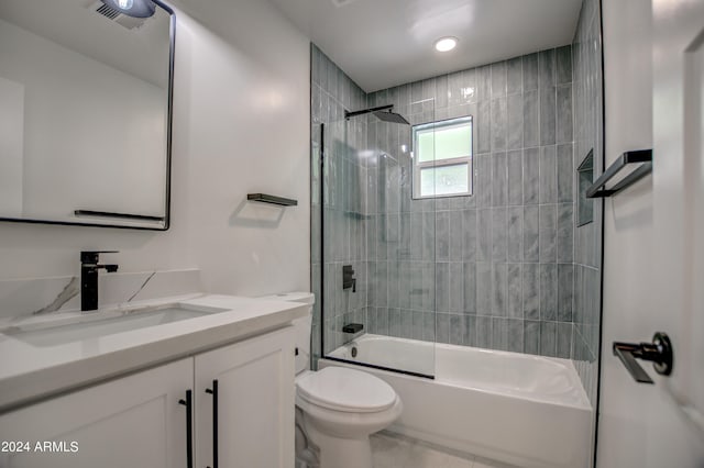 full bathroom with tile flooring, tiled shower / bath, vanity, and toilet