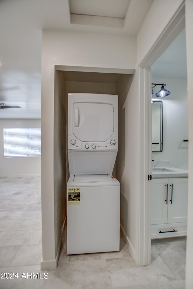 laundry room featuring stacked washer and dryer and light tile flooring