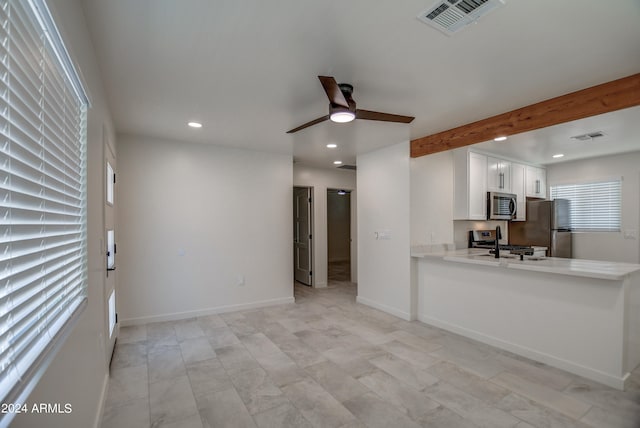 kitchen with appliances with stainless steel finishes, ceiling fan, beam ceiling, white cabinets, and light tile floors