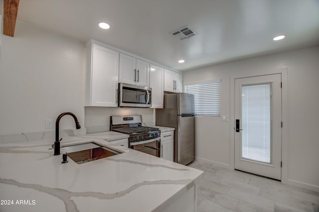 kitchen featuring appliances with stainless steel finishes, sink, a healthy amount of sunlight, and white cabinetry