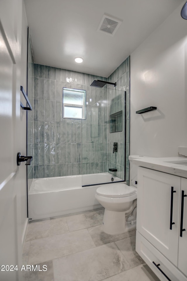 full bathroom featuring tiled shower / bath combo, vanity, tile floors, and toilet