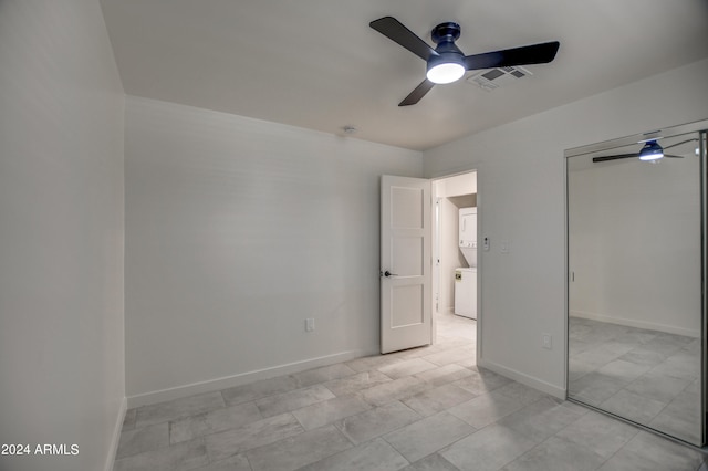 unfurnished bedroom featuring a closet, stacked washing maching and dryer, ceiling fan, and light tile floors