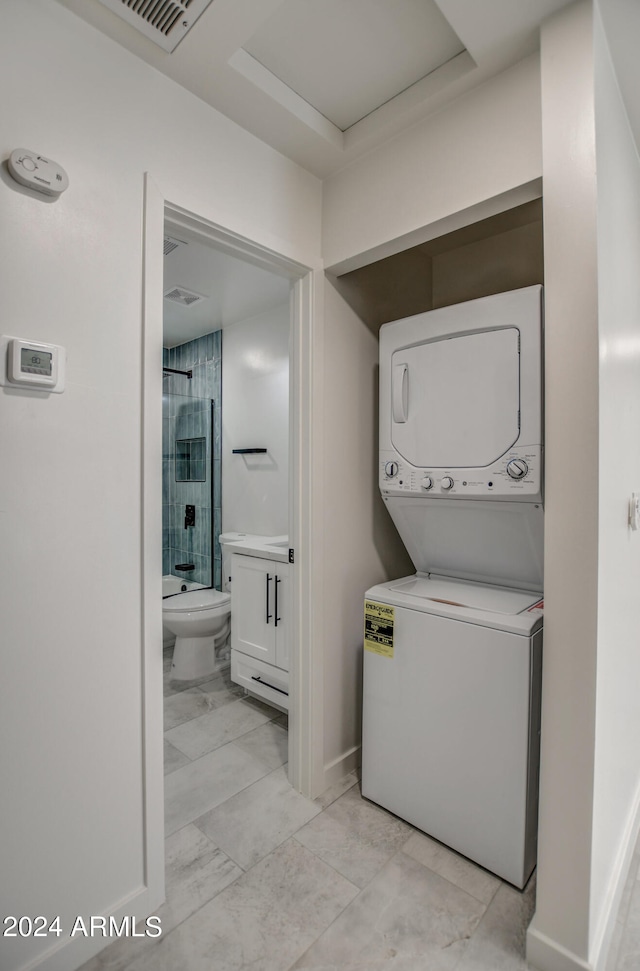 washroom featuring stacked washer / drying machine and light tile flooring