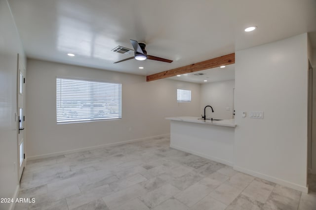 interior space with kitchen peninsula, ceiling fan, beam ceiling, sink, and light tile floors