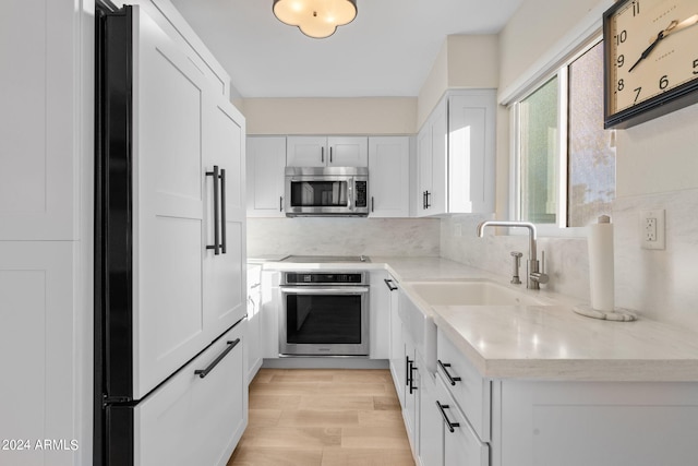 4620 N 68th St Unit 136, Scottsdale, AZ 85251 - kitchen featuring appliances with stainless steel finishes, white cabinetry, tasteful backsplash, light wood finished floors, and a sink
