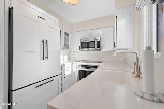 4620 N 68th St Unit 136, Scottsdale, AZ 85251 - kitchen with appliances with stainless steel finishes, a sink, white cabinets, light stone countertops, and glass insert cabinets