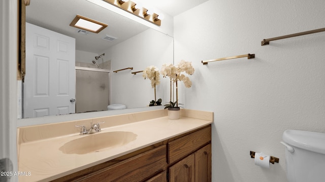 bathroom with toilet, a shower with door, and vanity