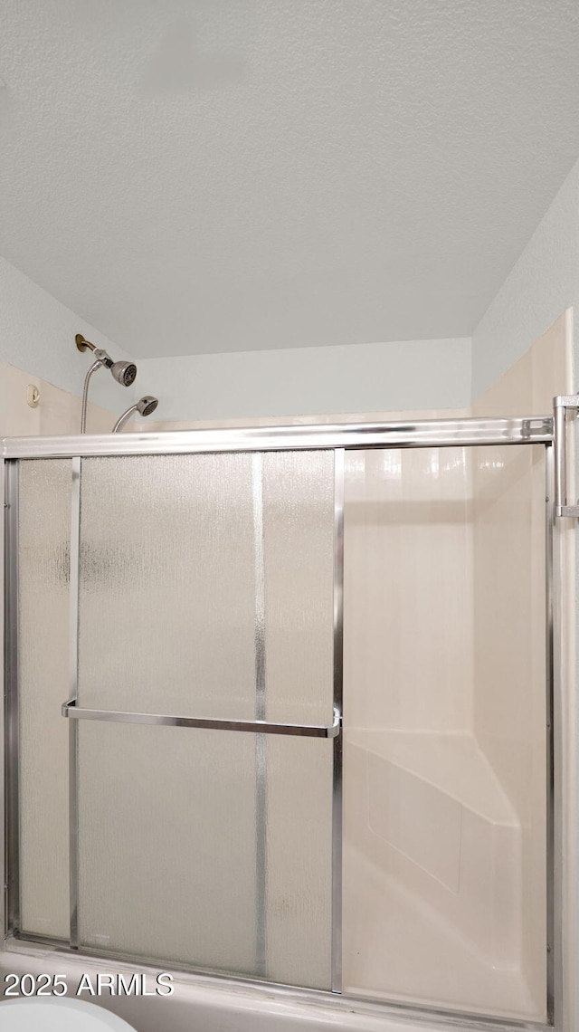 bathroom featuring a textured ceiling, toilet, and an enclosed shower