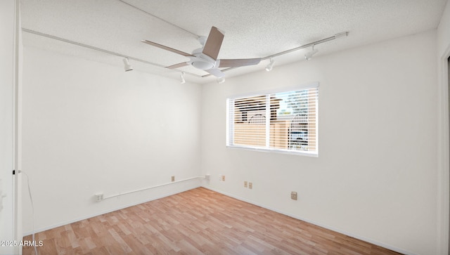 spare room featuring hardwood / wood-style flooring, ceiling fan, track lighting, and a textured ceiling