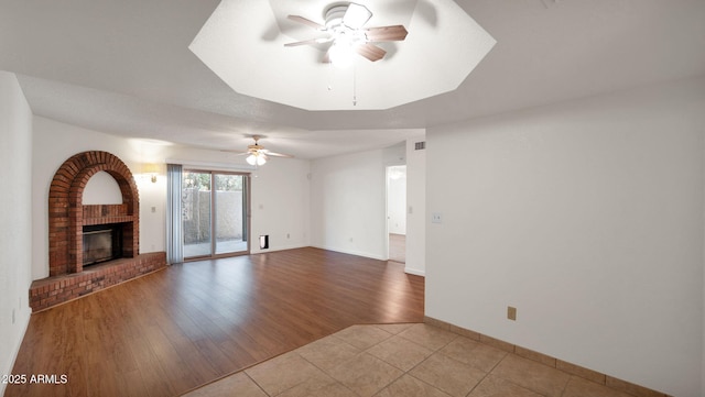 unfurnished living room featuring a fireplace, ceiling fan, and light hardwood / wood-style floors