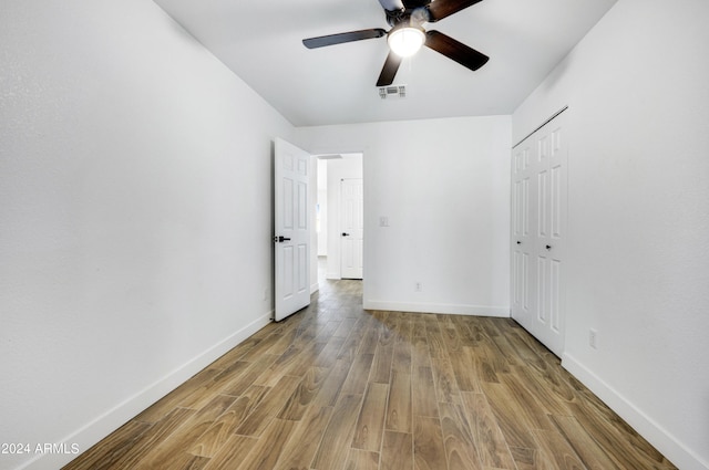 unfurnished bedroom featuring wood-type flooring, a closet, and ceiling fan