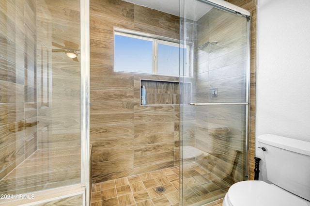 bathroom featuring a shower with door and toilet