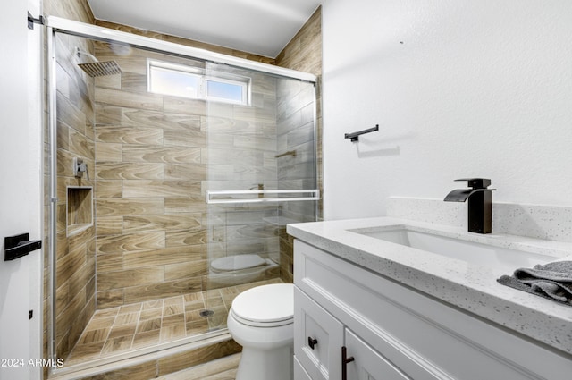 bathroom featuring vanity, toilet, and a shower with shower door