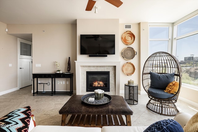 tiled living area with ceiling fan, baseboards, and a fireplace