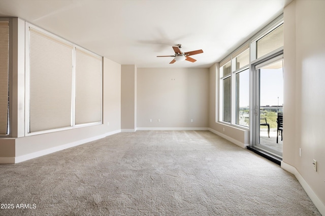 carpeted spare room featuring ceiling fan and baseboards