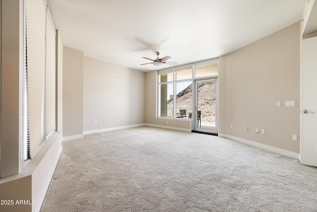 carpeted empty room with a ceiling fan and baseboards