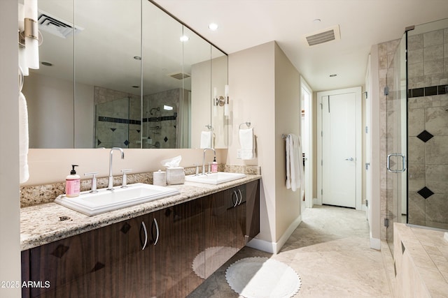bathroom featuring a stall shower, double vanity, and baseboards