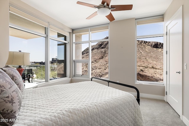 carpeted bedroom featuring a mountain view, baseboards, and a ceiling fan