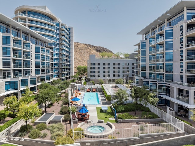 exterior space with a pool, apartment complex / building, and mountains