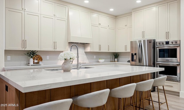 kitchen featuring stainless steel appliances, tasteful backsplash, light stone counters, and a kitchen bar