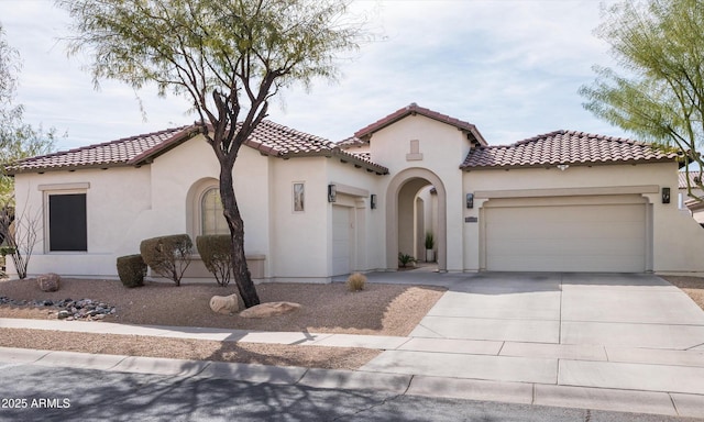 mediterranean / spanish home with a tile roof, driveway, an attached garage, and stucco siding