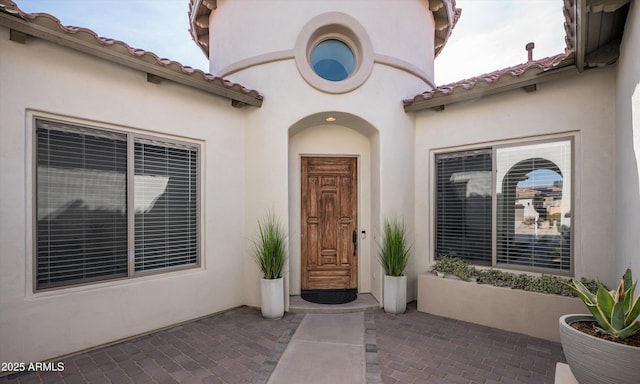 property entrance with a patio, a tiled roof, and stucco siding