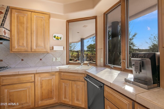 kitchen featuring tasteful backsplash, stainless steel dishwasher, tile counters, and sink