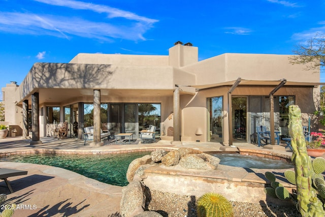 rear view of house featuring a swimming pool with hot tub and a patio area