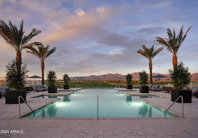 pool at dusk with a patio area and a mountain view