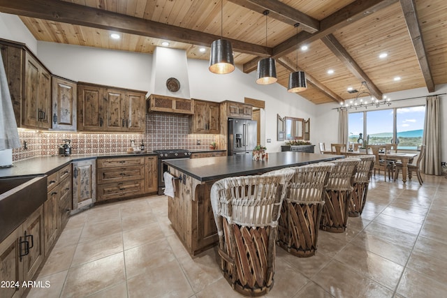 kitchen featuring stainless steel refrigerator with ice dispenser, decorative light fixtures, beamed ceiling, range, and a center island