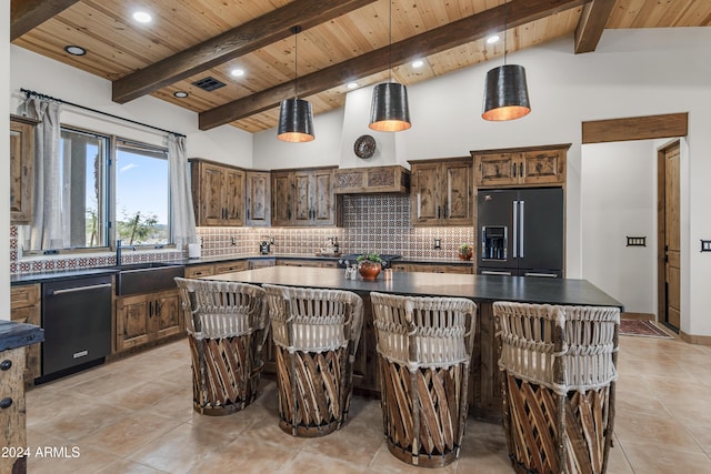 kitchen with decorative backsplash, appliances with stainless steel finishes, a center island, decorative light fixtures, and vaulted ceiling with beams