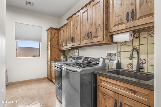 laundry area with cabinets, light tile patterned floors, washing machine and dryer, and sink