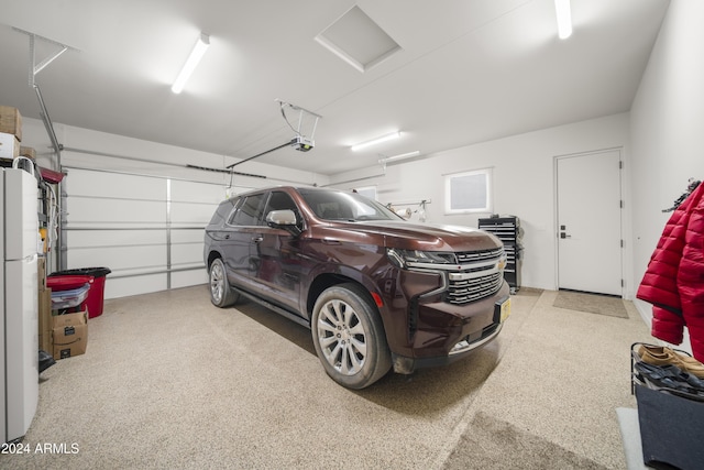 garage featuring white refrigerator and a garage door opener