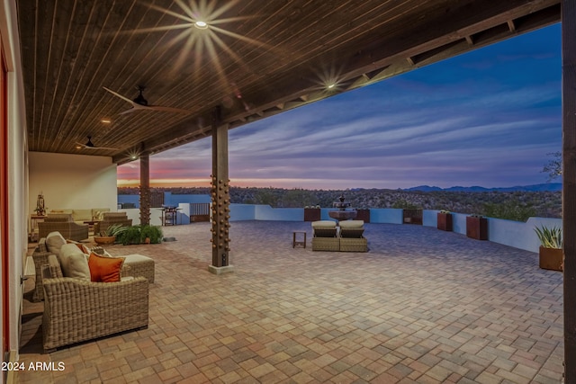 patio terrace at dusk featuring ceiling fan and an outdoor living space